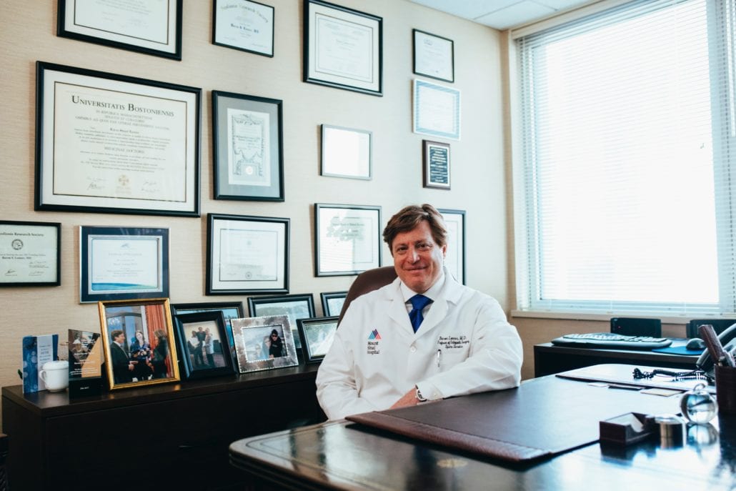 smiling man in white shirt sitting behind desk